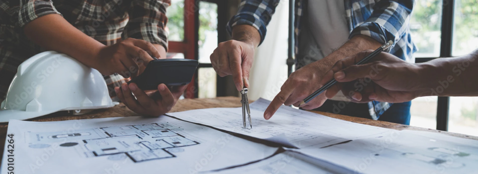 ampliare casa: tre persone con compasso matita e calcolatrice in mano sono intenti a misurare correttamente su un progetto di casa