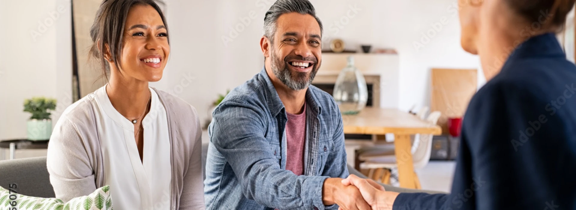 due possibili compratori stringono la mano a uno degli agenti immobiliari di spalle nella loro possibile futura casa